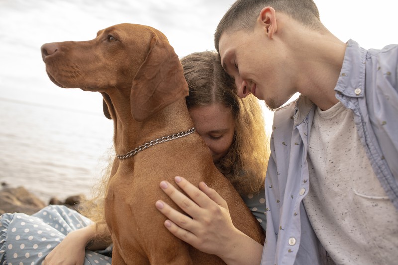 Paar kuschelt glücklich mit seinem Hund