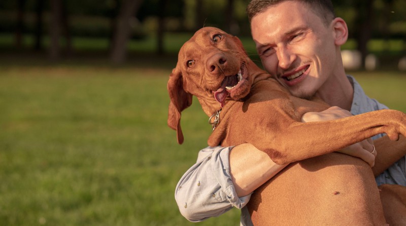 Ein Mann kuschelt liebevoll mit seiner Hündin.
